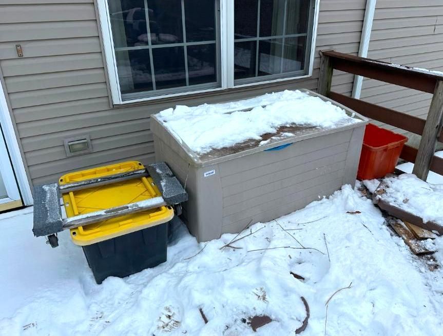 Snowy deck with plastic storage bins.