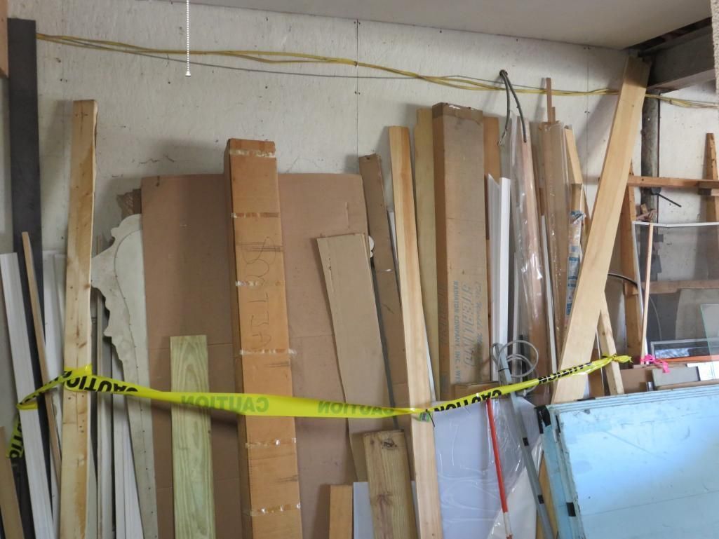 Pile of lumber and materials against a wall, with caution tape across the front.