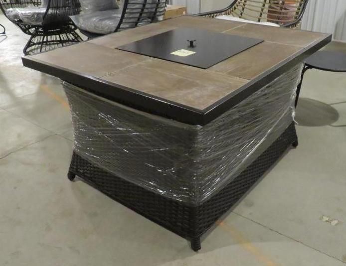 Rectangular outdoor fire pit table, tile top, wicker base, black metal burner cover.