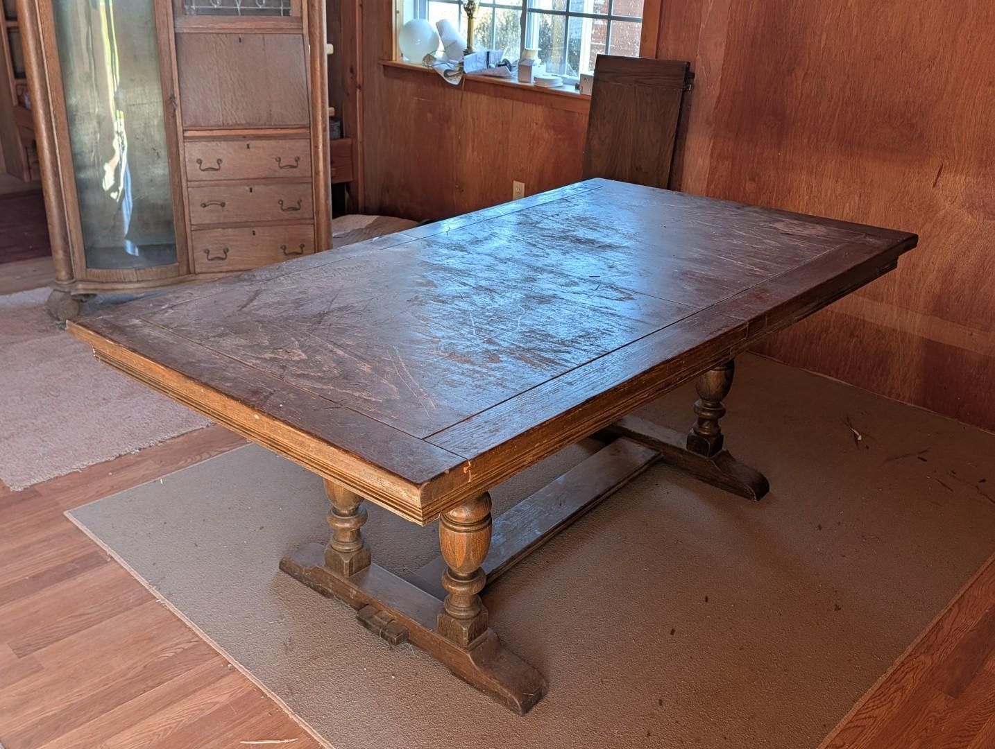 Wooden dining table with turned legs in a wood-paneled room