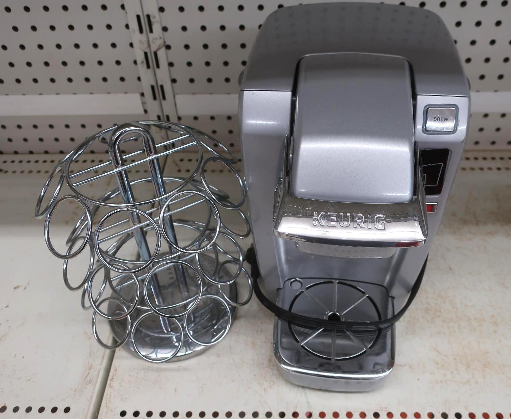 Silver Keurig coffee maker with a K-Cup carousel on a shelf.