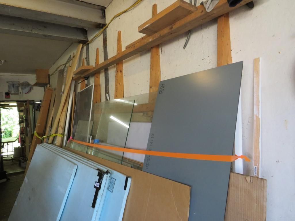 Assorted sheets of building materials stored against a wall in a workshop.