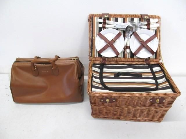Brown leather bag beside an open wicker picnic basket with plates and utensils.