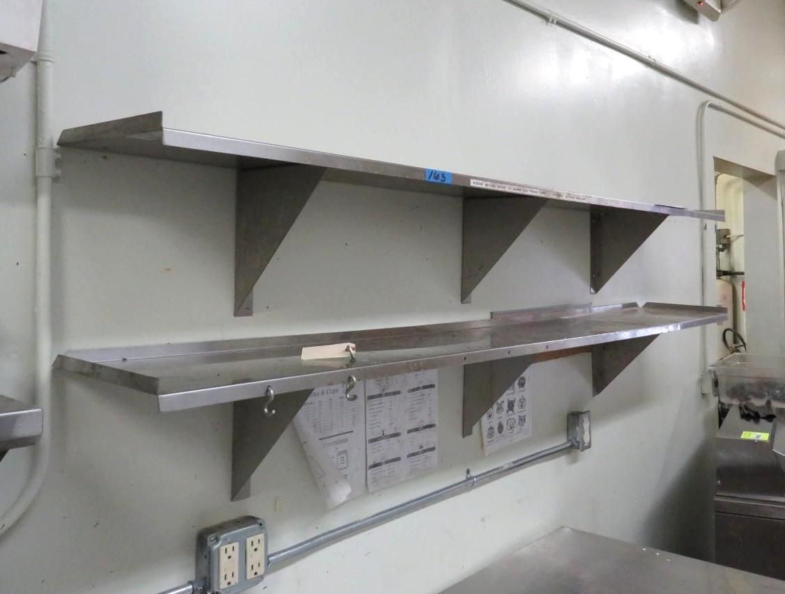Stainless steel shelves mounted on a wall in a kitchen.
