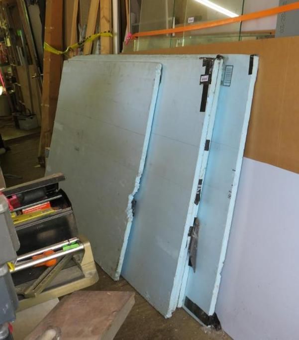 Stack of light blue foam insulation boards leaning against a wall in a workshop.