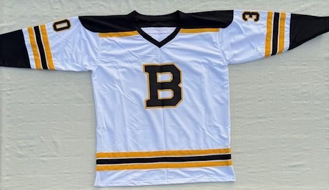 White hockey jersey with black and gold trim, featuring a large