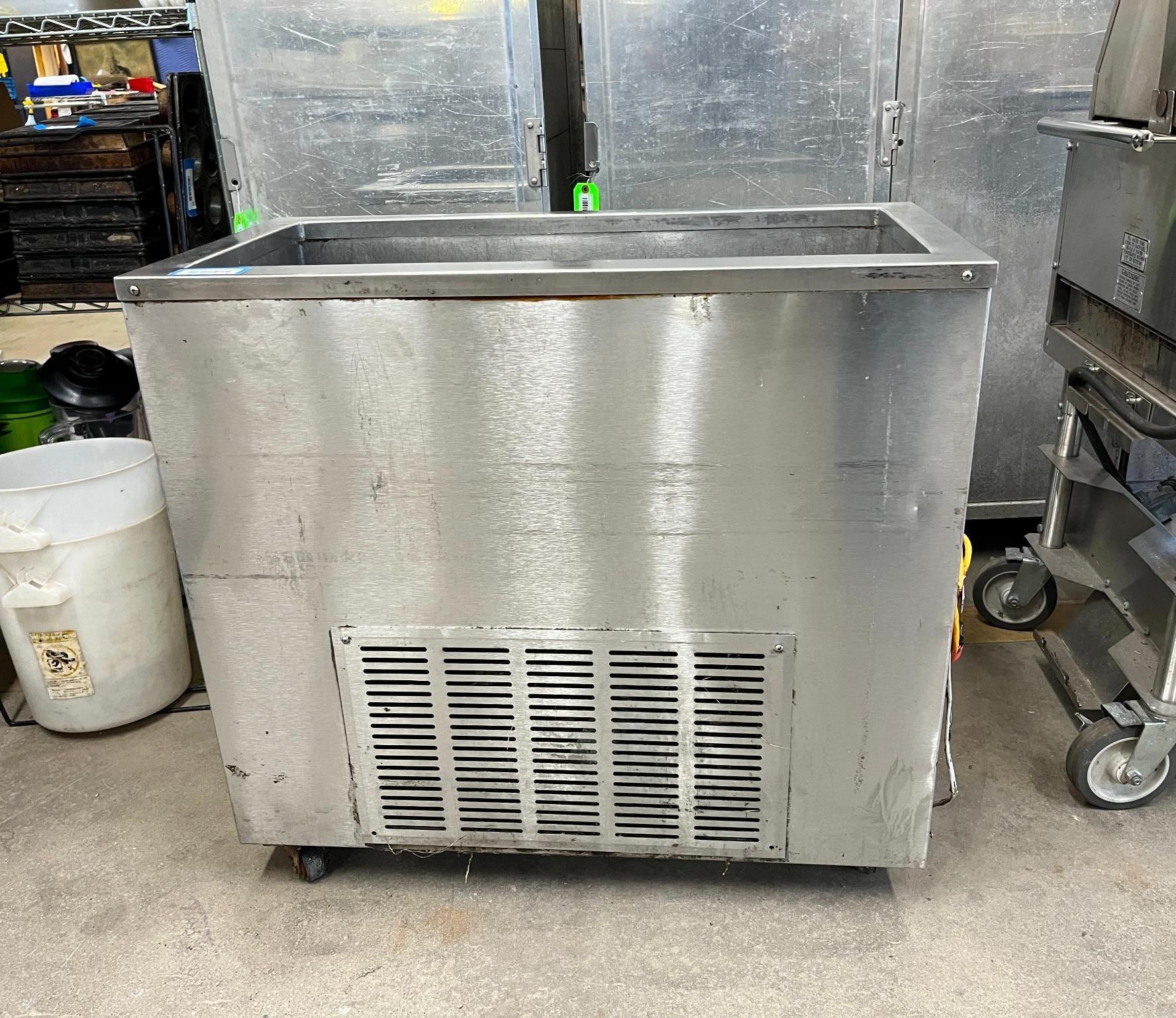 Stainless steel commercial freezer with open top, ventilation grill, and wheels.