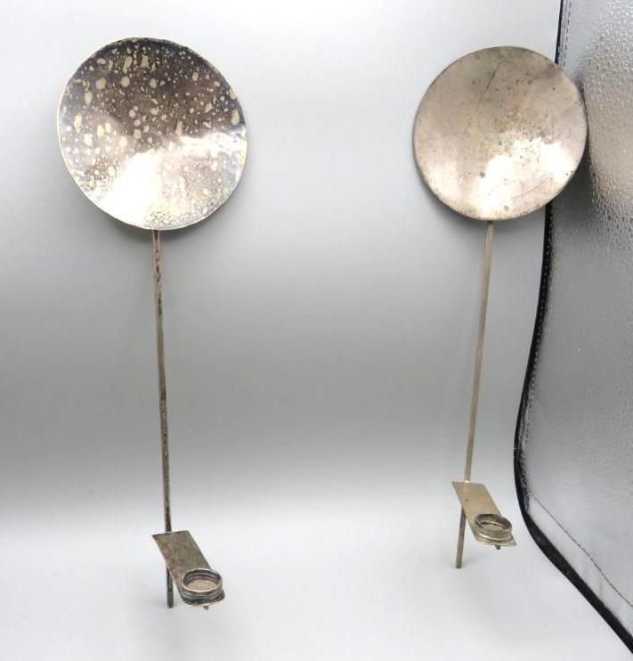 Two silver wall sconces with circular shades and rectangular bases.