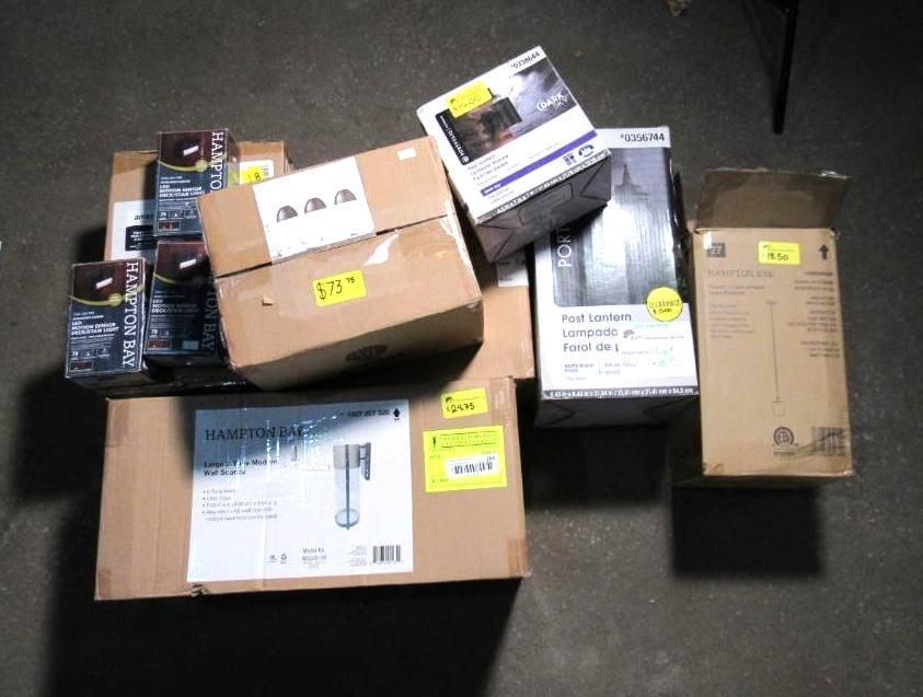Cardboard boxes with various household items on a floor, some with price tags.