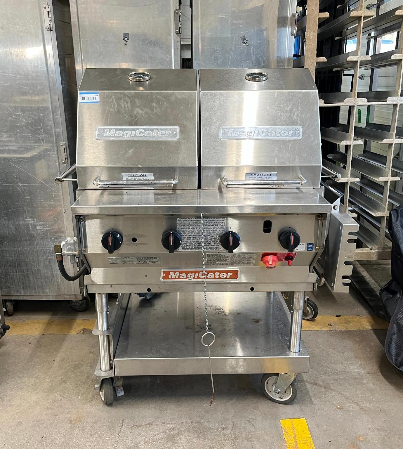 Stainless steel commercial grill with two hinged covers, mounted on a rolling cart.