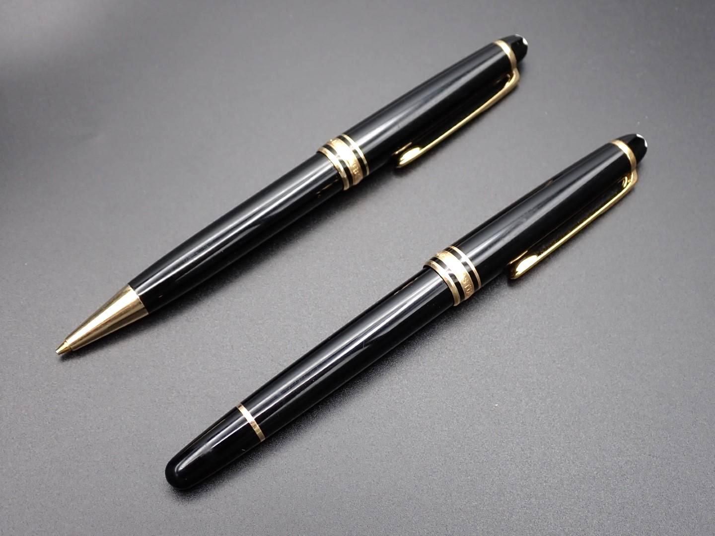 Two black pens with gold accents on a dark surface.