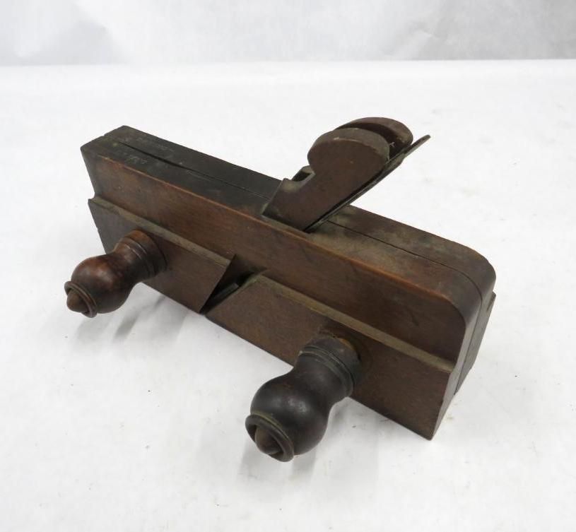 Wooden rabbet plane tool with dark stain, two side handles, and angled blade.