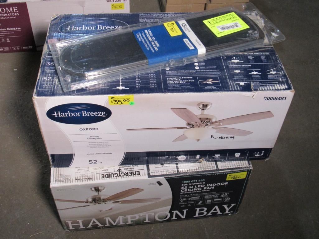 Two Hampton Bay ceiling fan boxes, one with an accessory on top, on a gray surface.