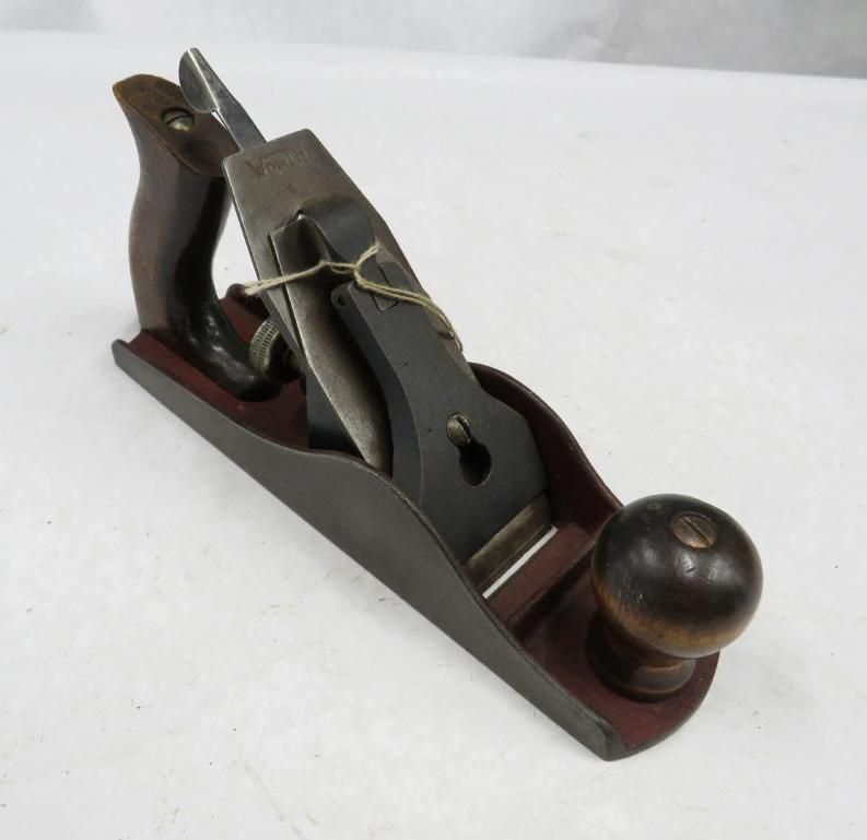 Wooden hand plane on a light surface. Dark wood body, blade exposed.