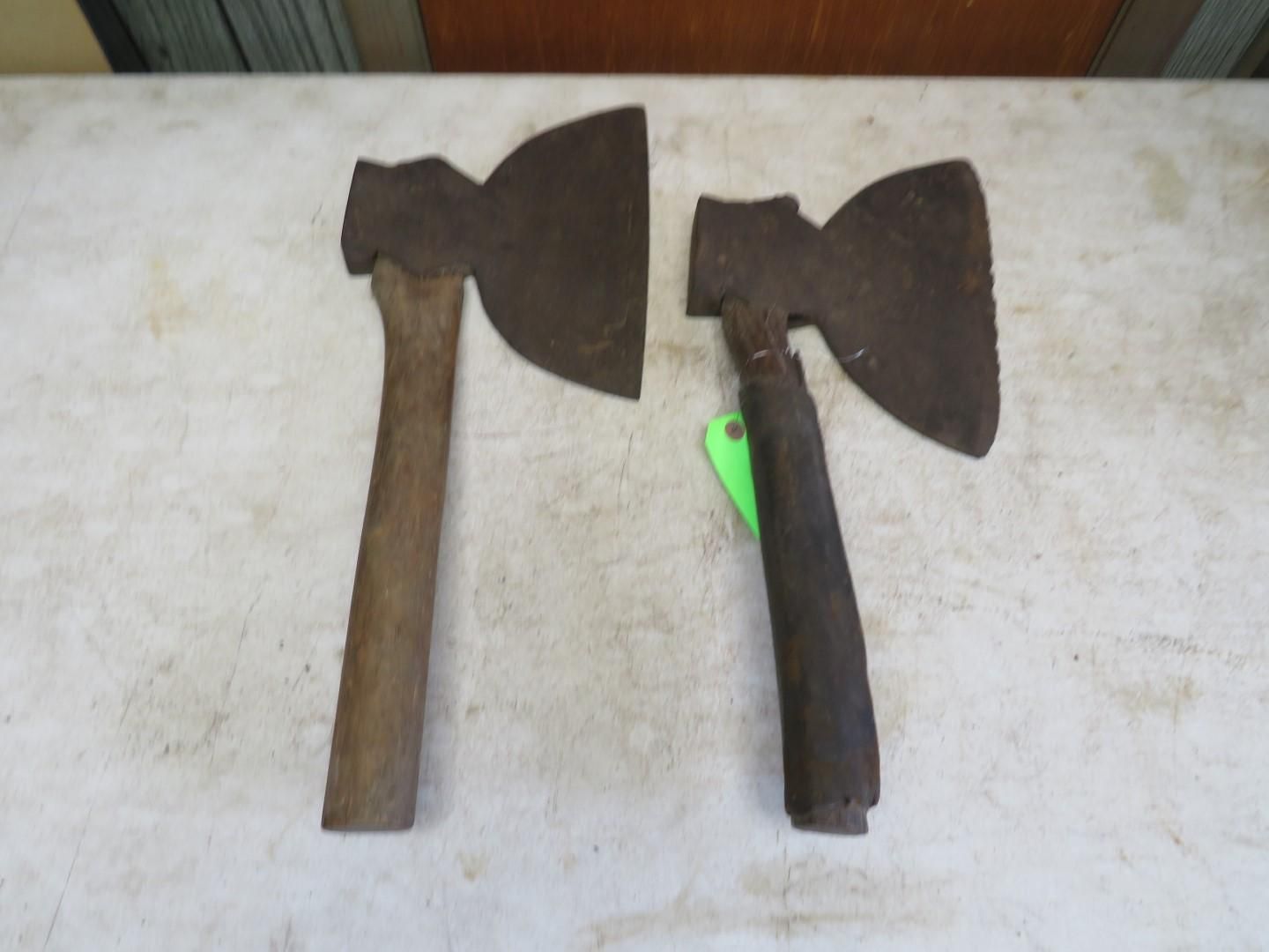Two hatchets with wooden handles on a white surface.