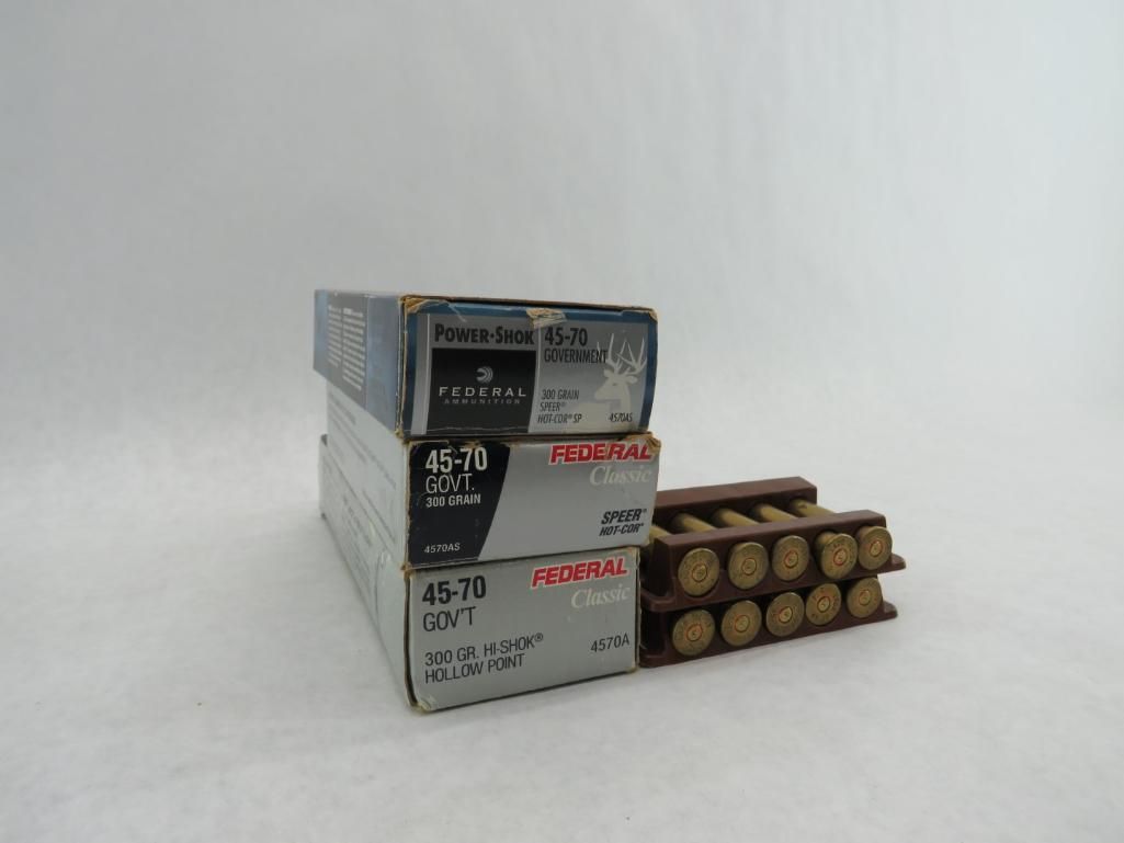 Three boxes of ammunition stacked next to a wooden cartridge holder with multiple cartridges.