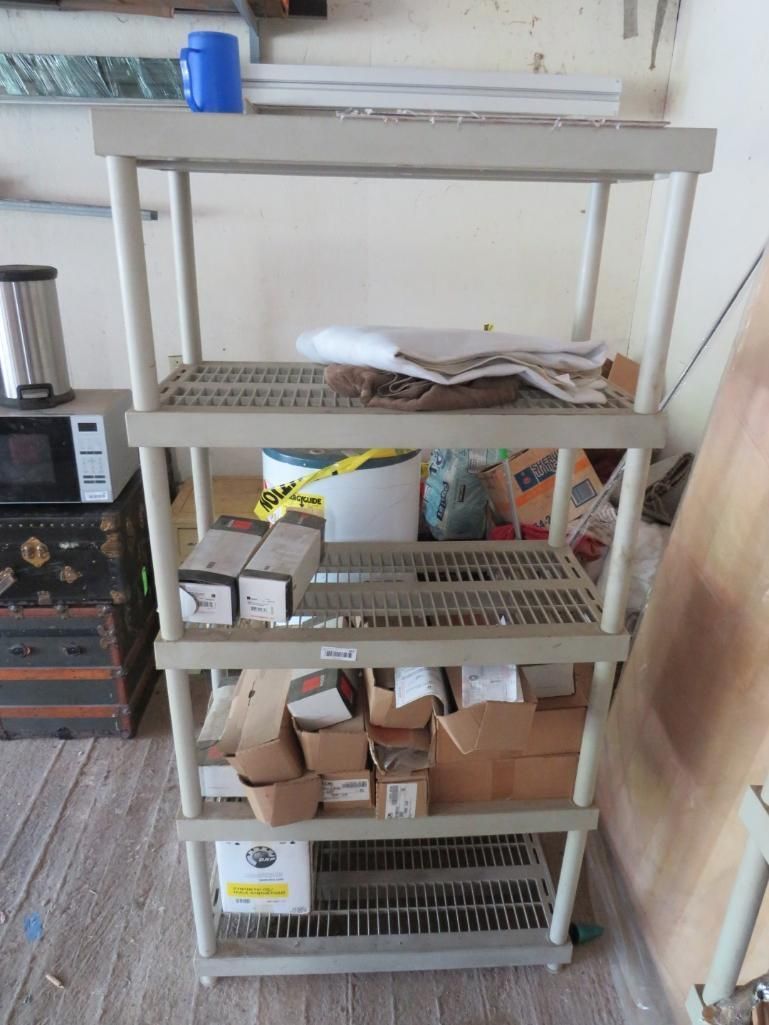 Beige plastic shelving unit with miscellaneous items on shelves, indoors.