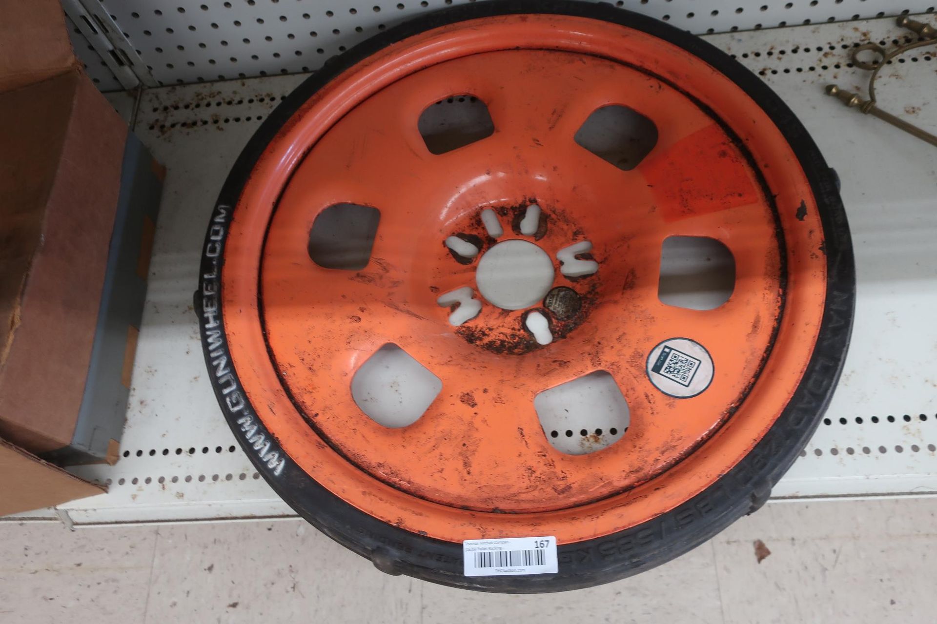 Orange spare tire with black tire. Sticker and barcode visible.