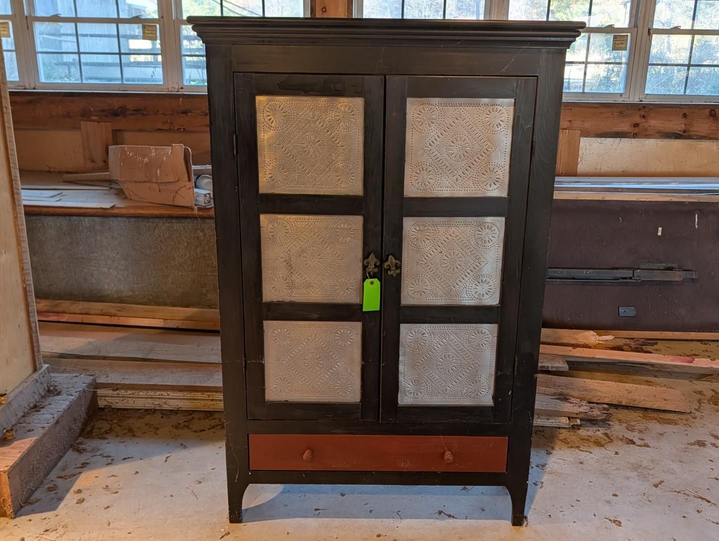 Dark wooden cabinet with frosted glass panels and a green lock in a workshop setting