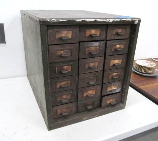 A vintage metal cabinet with multiple small wooden drawers; brown and gray tones.