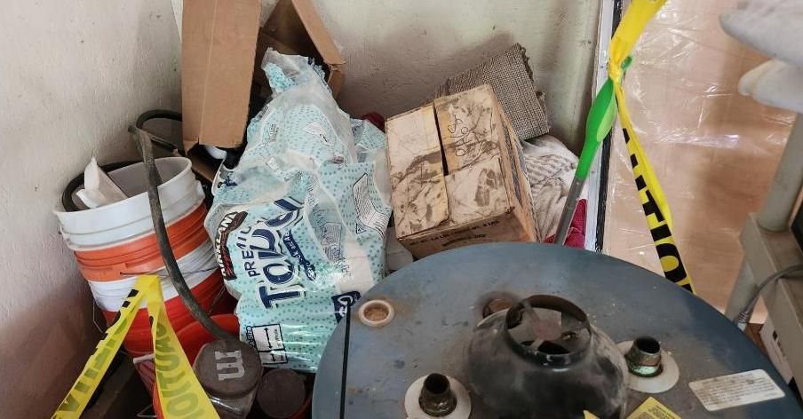 Storage area with water heater, boxes, bag, wood blocks, and warning tape.