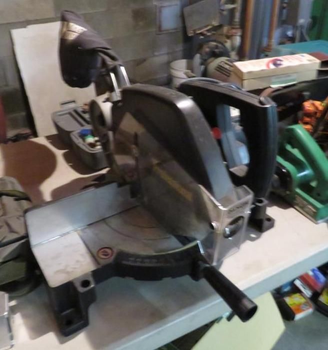 Miter saw on a table; black, silver and gray; another green saw in the background.