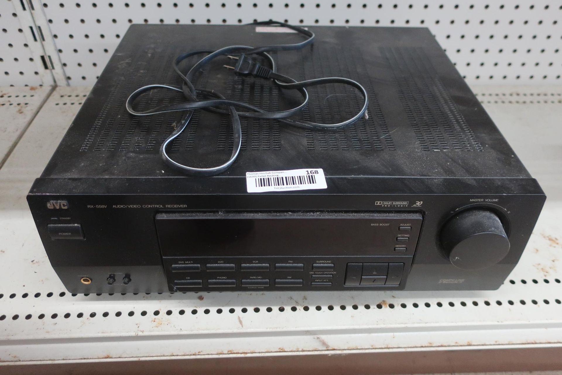 Black JVC receiver with buttons and a power cord on a shelf.