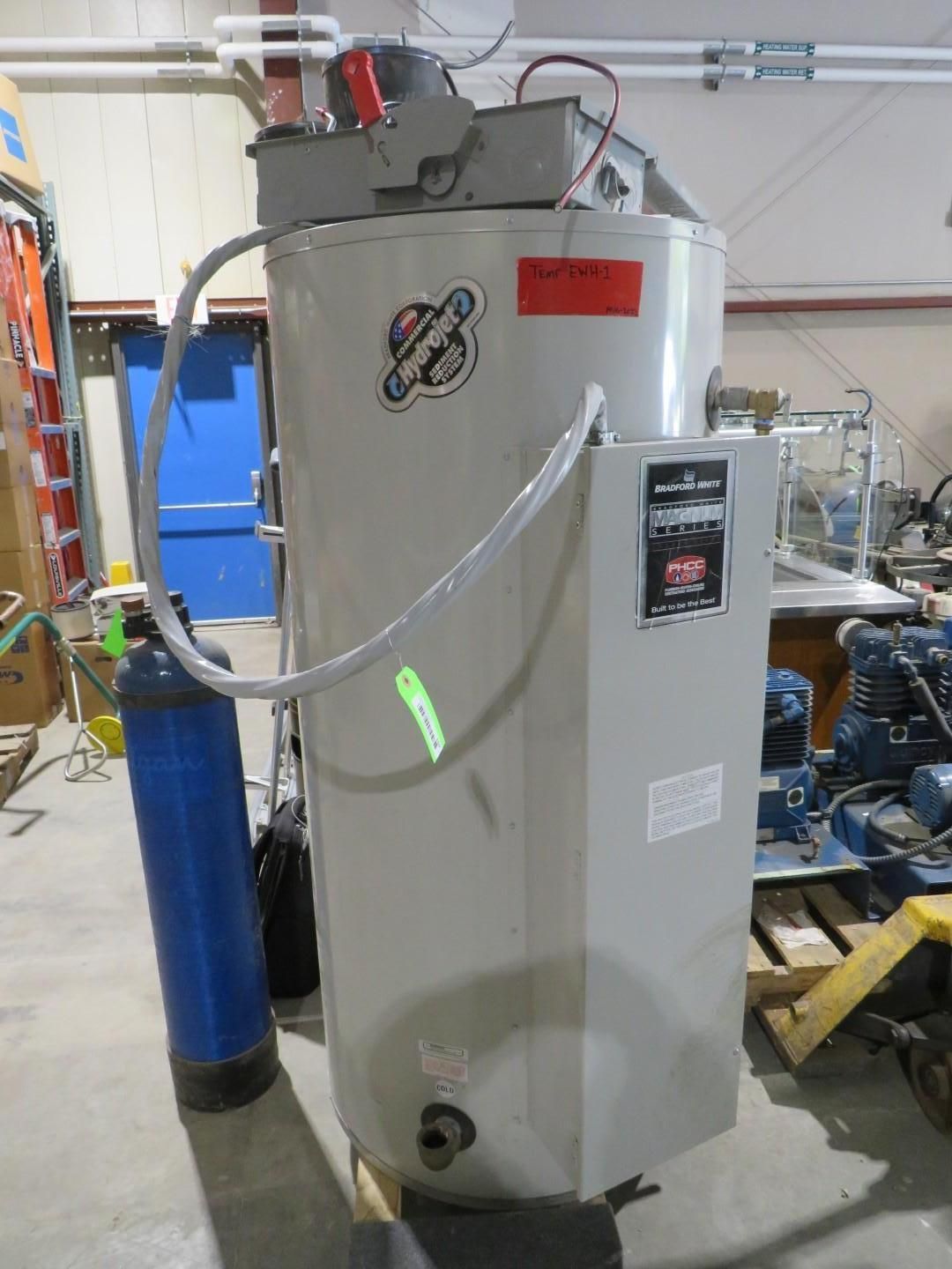 A large gray water heater with a blue water filter beside it; in an industrial setting.
