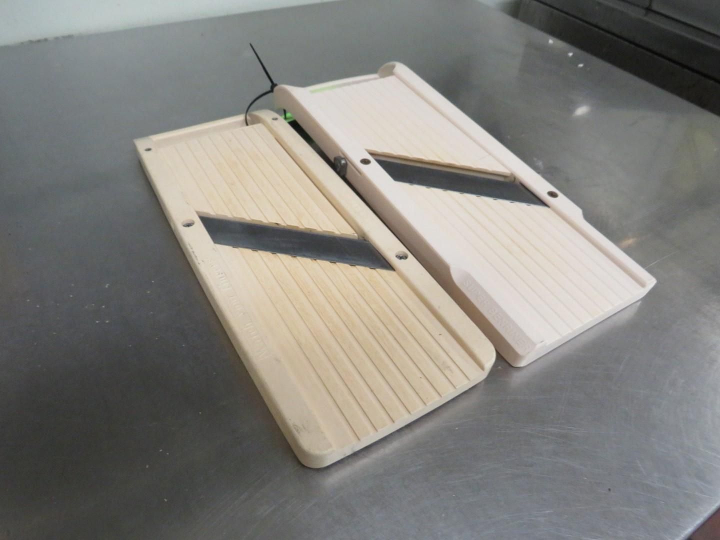 Two wooden mandoline slicers on a stainless steel surface, showing blades.