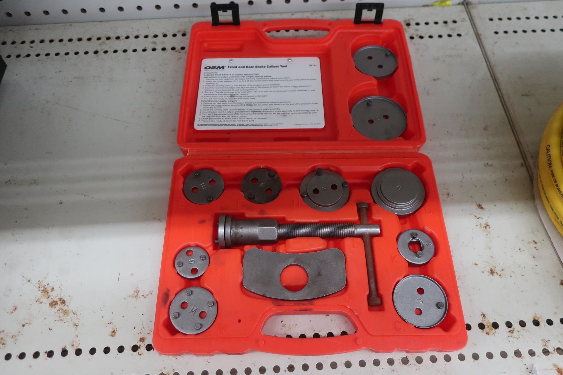 Open orange case holding brake caliper tool set with various attachments.