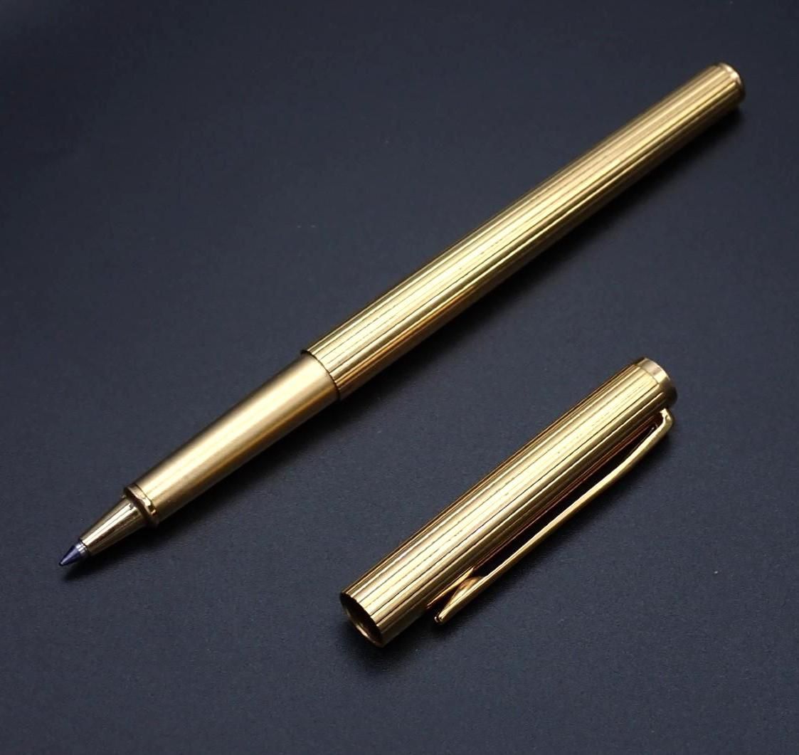 Gold pen with matching cap on a black surface.