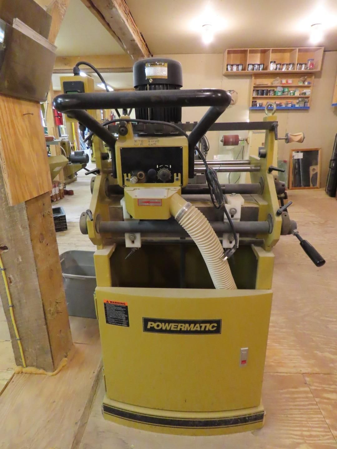 Yellow Powermatic woodworking machine in a shop, with dust hoses attached