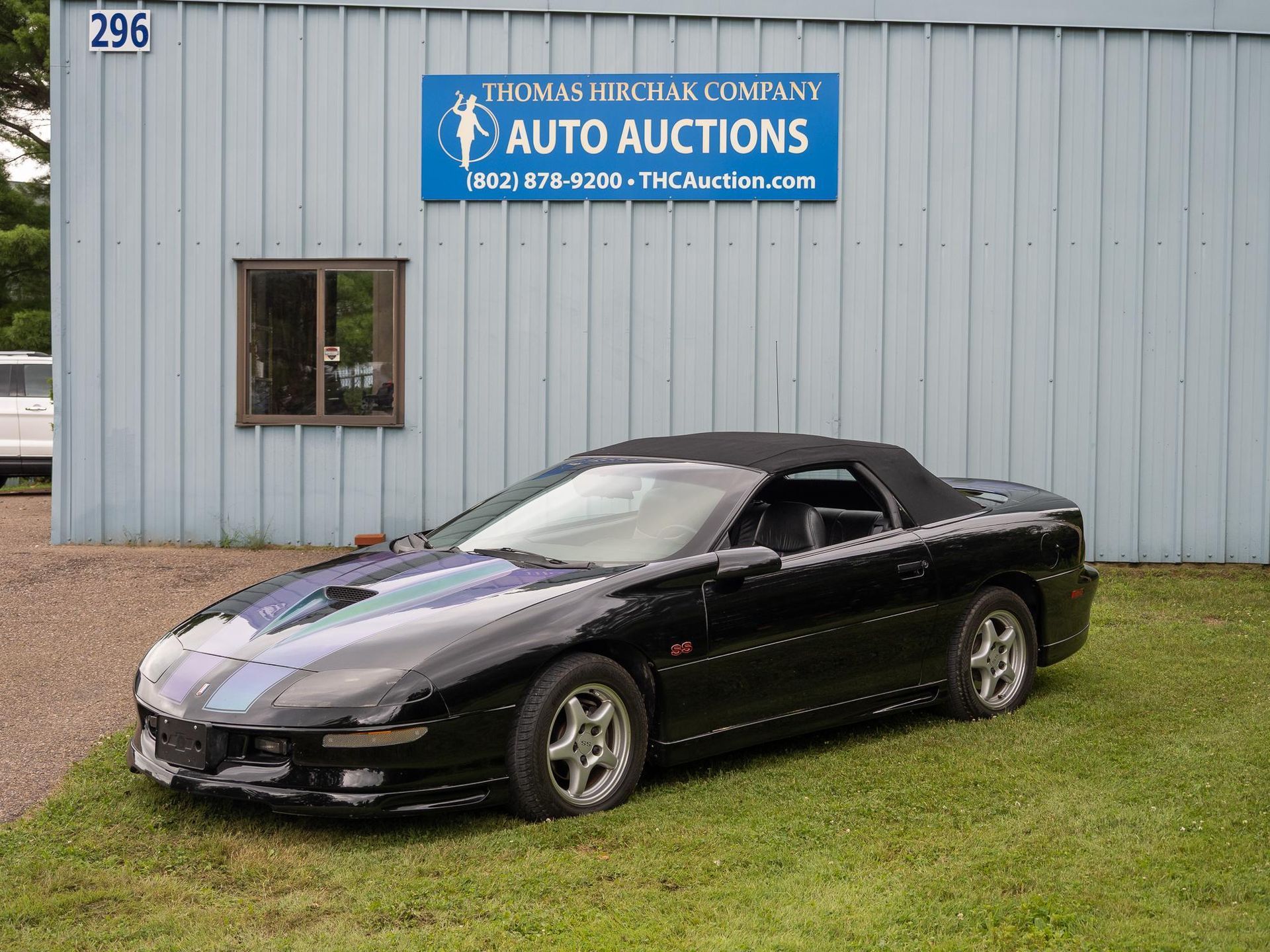 Black convertible car parked in front of an auto auction building.
