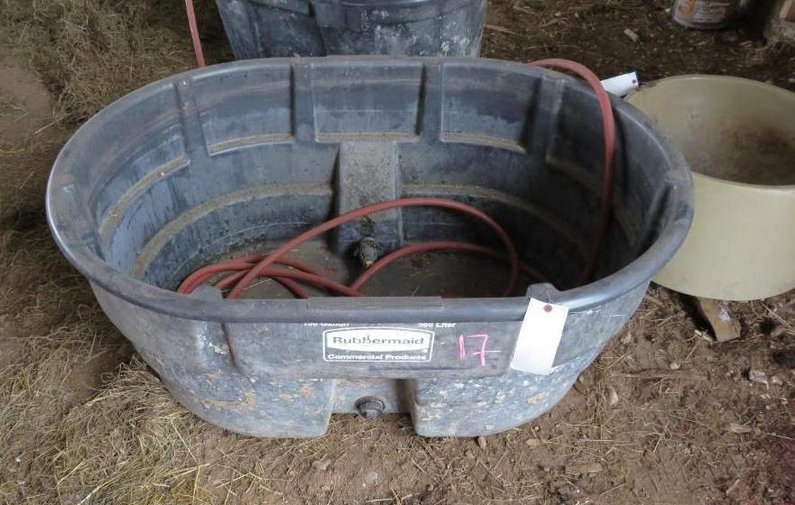 A large black water trough with a red hose.