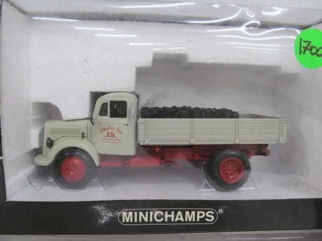 Toy truck model in packaging. Beige cab and bed, red chassis and wheels. Load of black coal.
