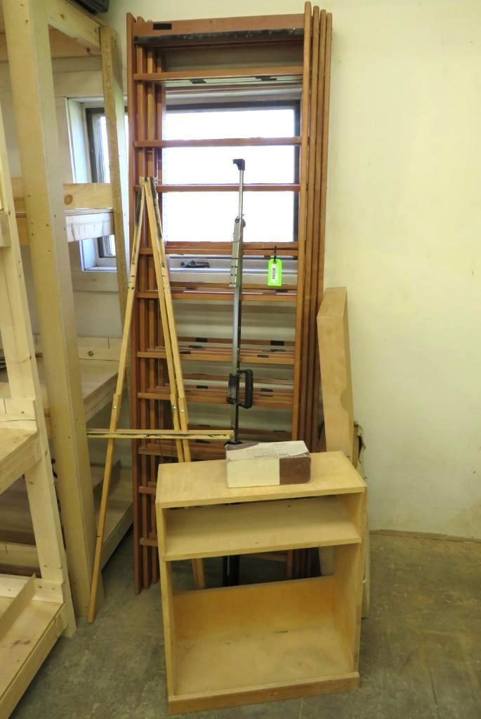 Assorted wooden shelving, a ladder, and a small bookcase stand in a room.