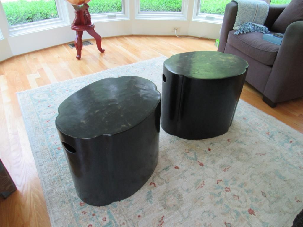 Two black, cylindrical side tables on a patterned rug in a sunlit room.