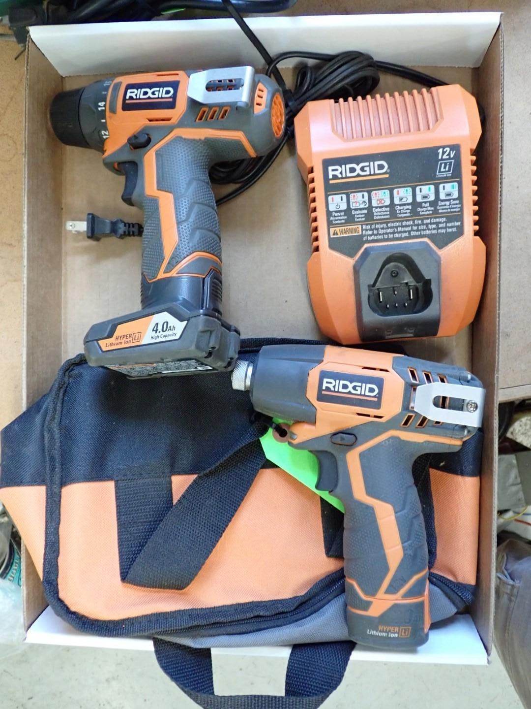 Ridgid power tool set: drill, impact driver, charger, battery, and tool bag, orange and black.