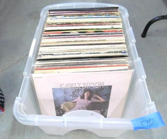 A clear plastic storage bin filled with vinyl records, including a Carly Simon album.