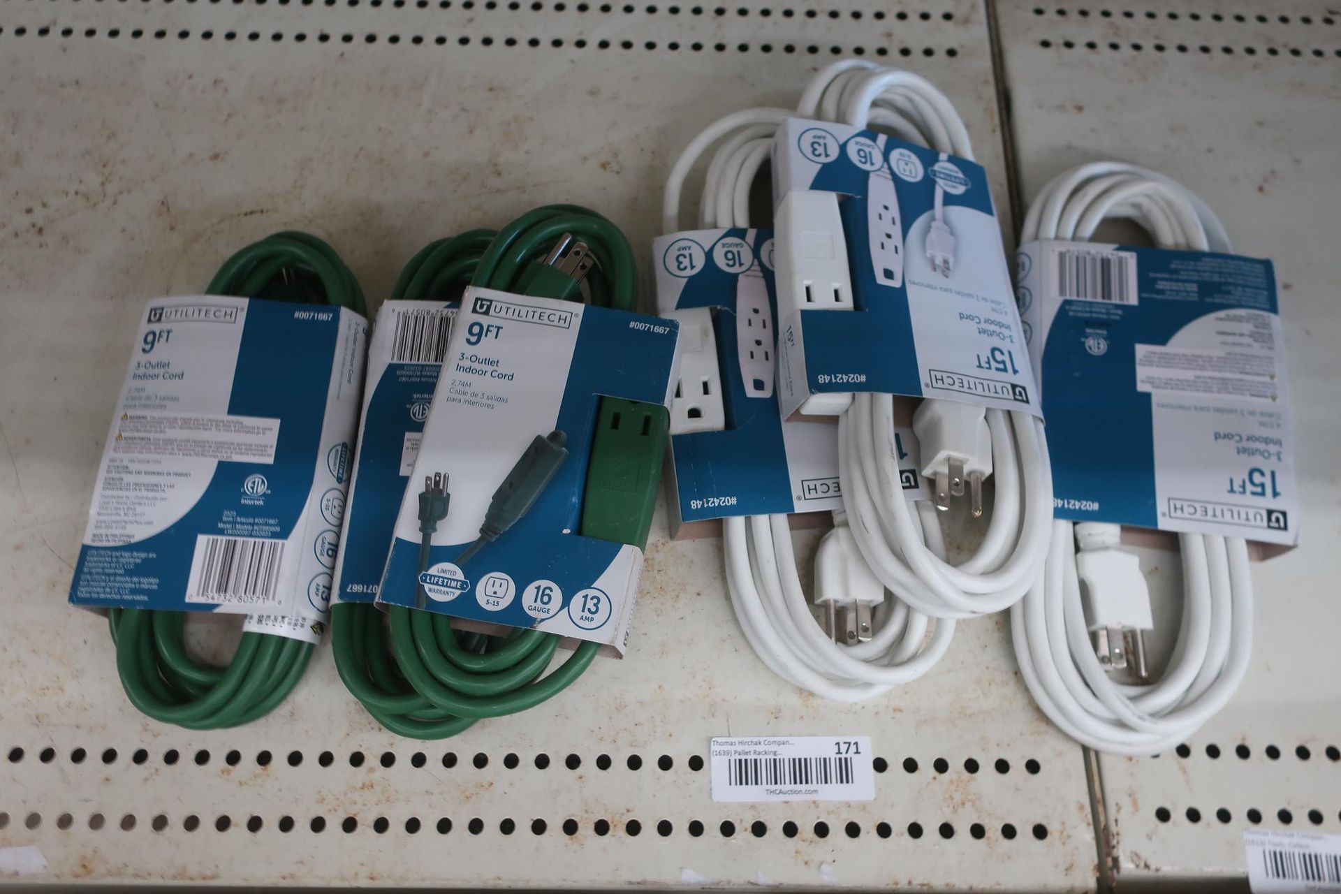 Green and white extension cords on a shelf with packaging.