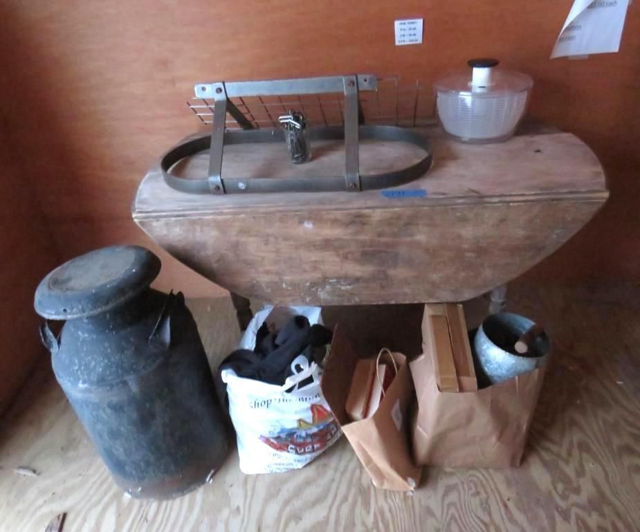 Vintage objects: milk can, wooden table, glass bowl, and bags in a wooden enclosure.