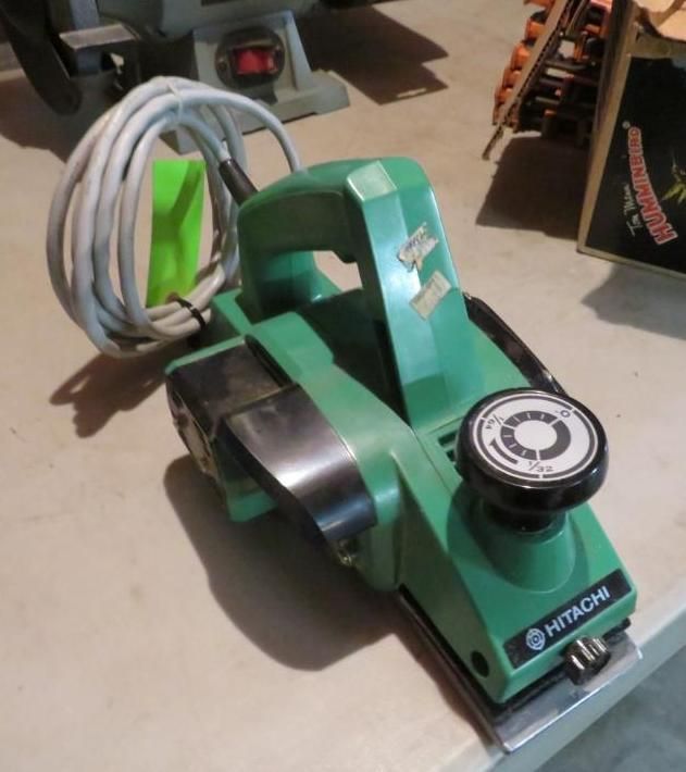 Green Hitachi electric hand planer on a table with a coiled white cord.