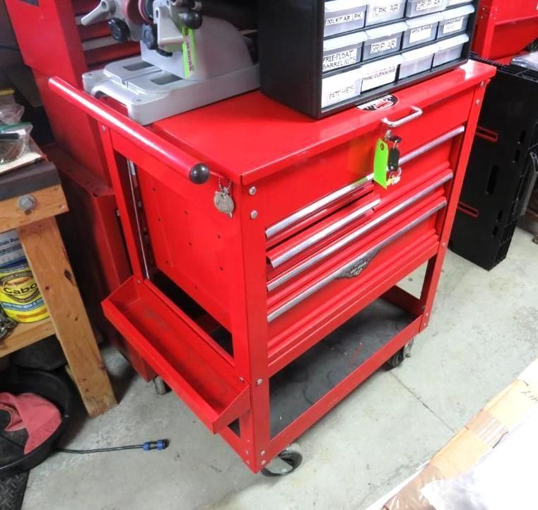 Red tool cabinet with drawers, side tray, and casters, in a workshop setting.