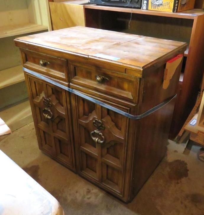 Wooden cabinet with two drawers and two doors, ornate carvings, metal handles, and brown finish.