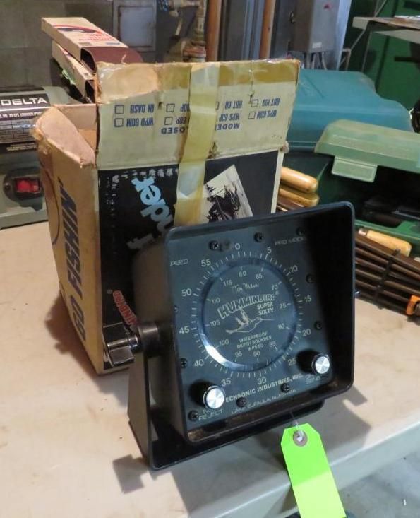 Black fish finder with original box, green tag, sitting on a table.