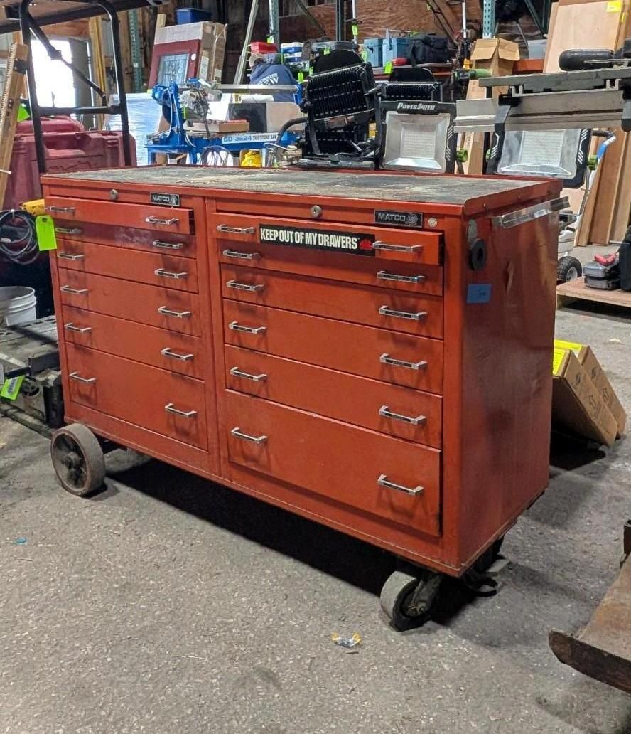 Orange tool chest with many drawers on casters in a workshop.