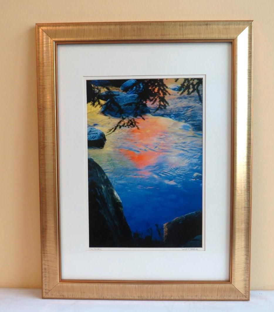 Framed art: Colorful reflection of a sunset in water. Blue, orange, and black tones.