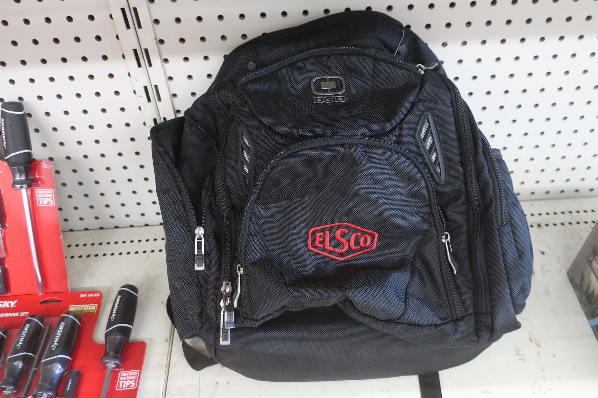 Black ELSCO backpack on a shelf with tools in a store.