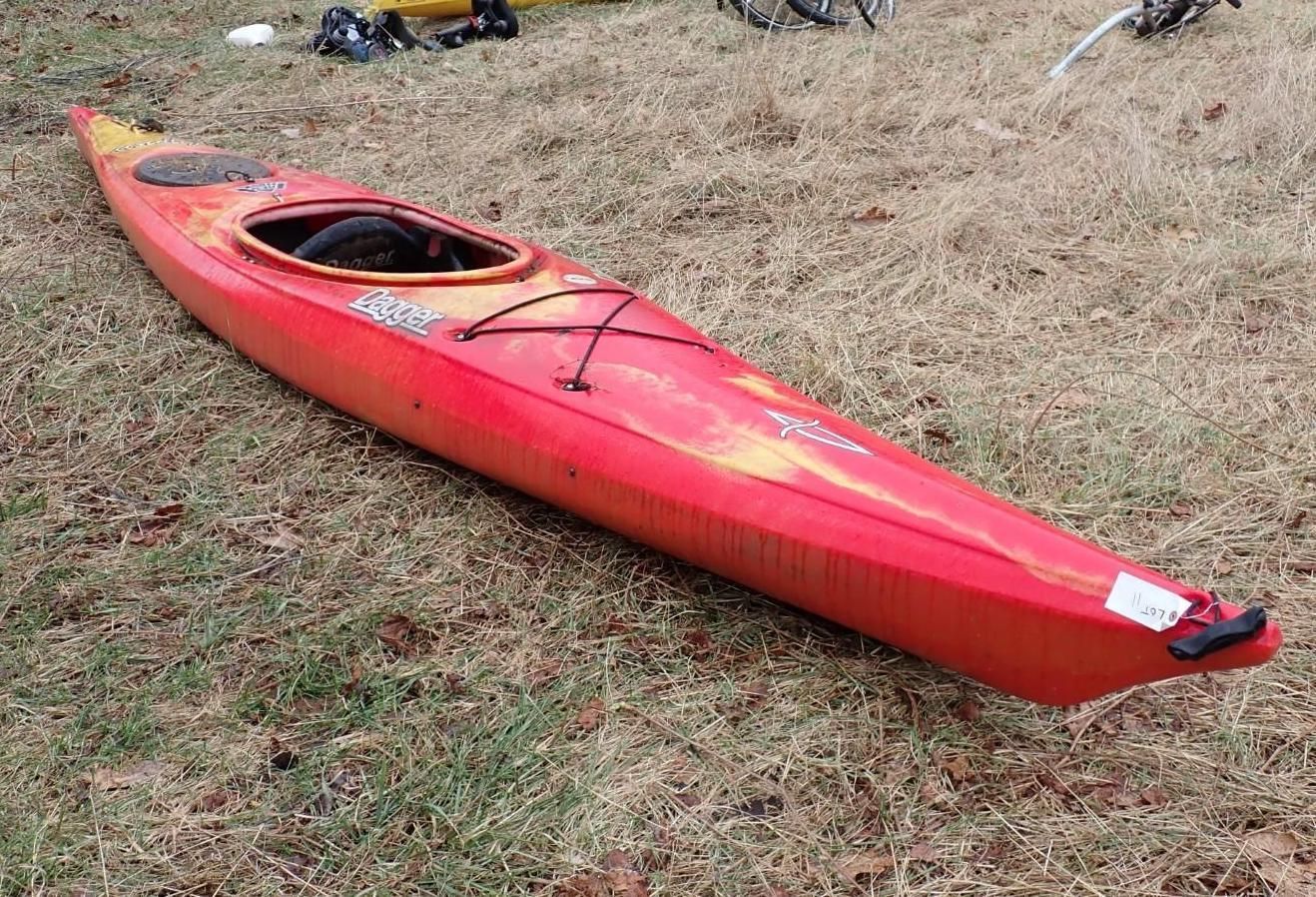 A red and orange recreational kayak resting on grass.