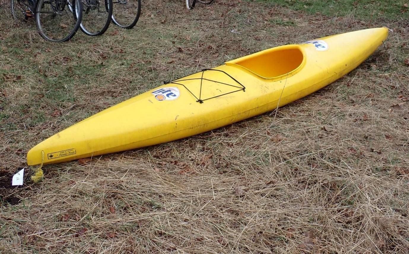 A yellow kayak resting on a patch of grass.